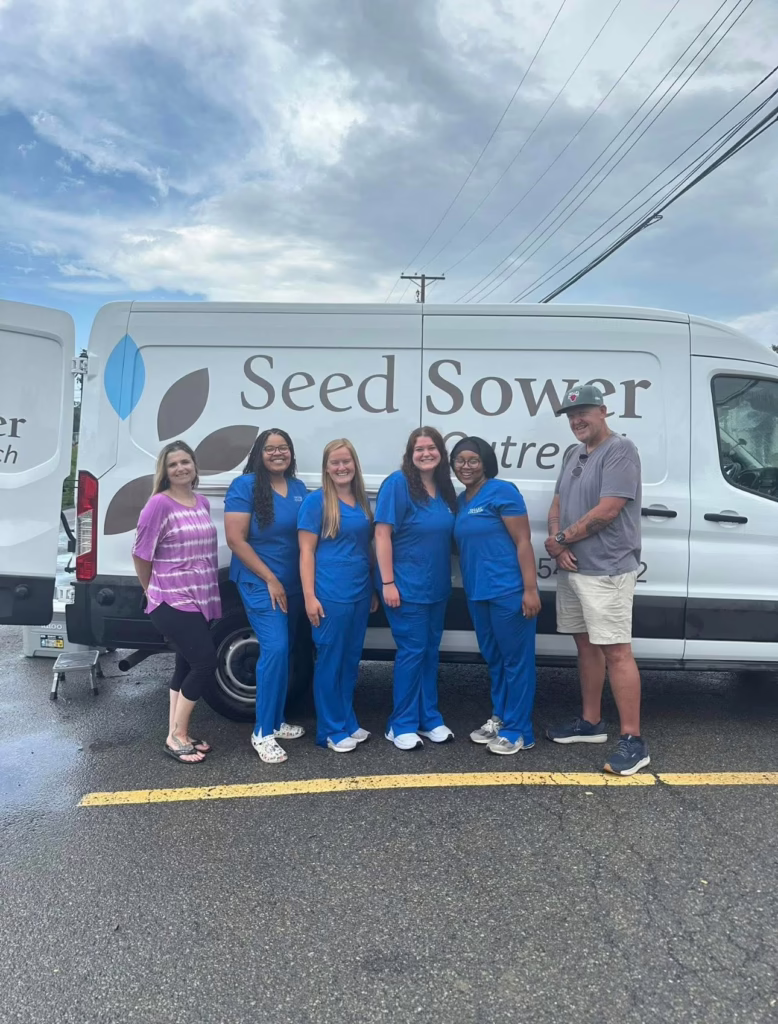 Individuals standing in front of a Seed Sowers van.